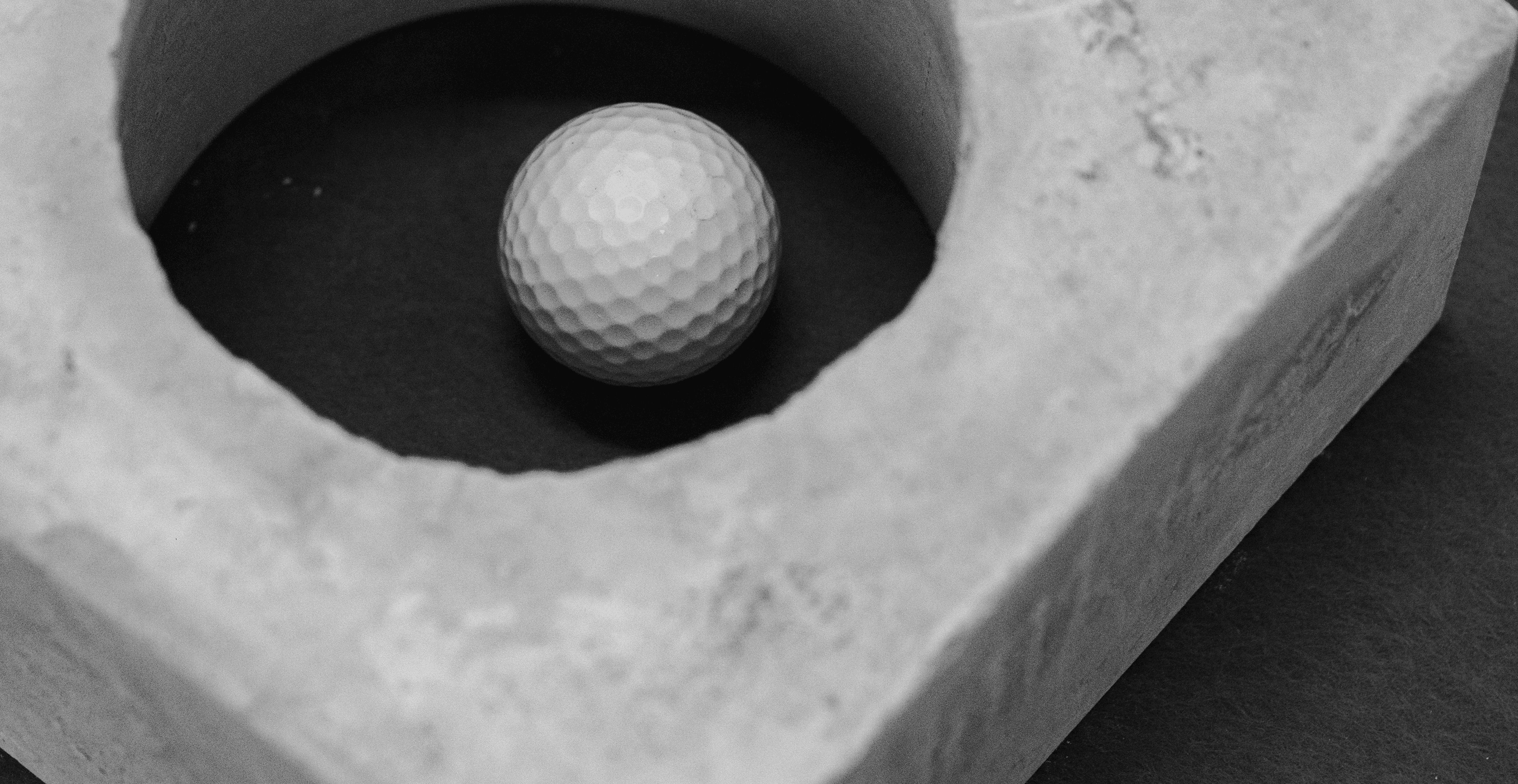 A golf ball resting in a concrete hole